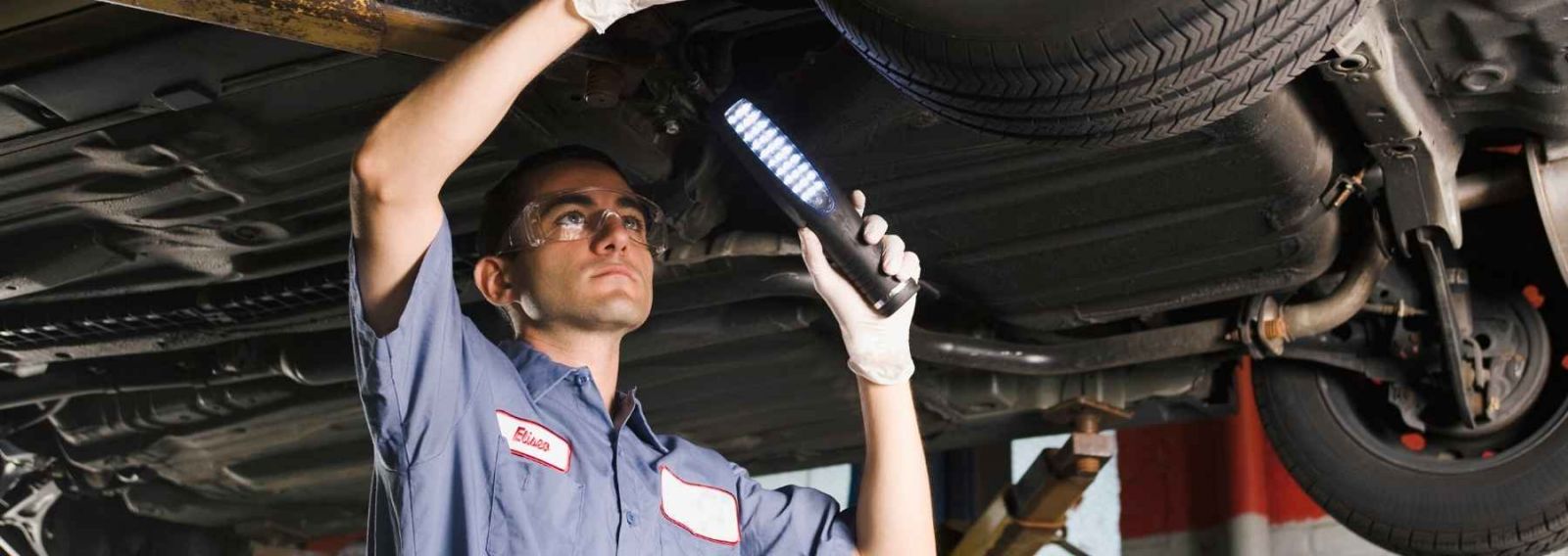 man working underneath a car in auto shop
